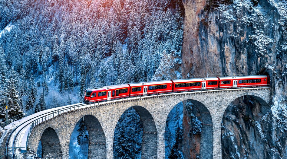 Vue aérienne du train traversant la célèbre montagne à Filisur, Suisse. Train Express dans les Alpes suisses paysage hivernal enneigé. | © Shutterstock 2256994783